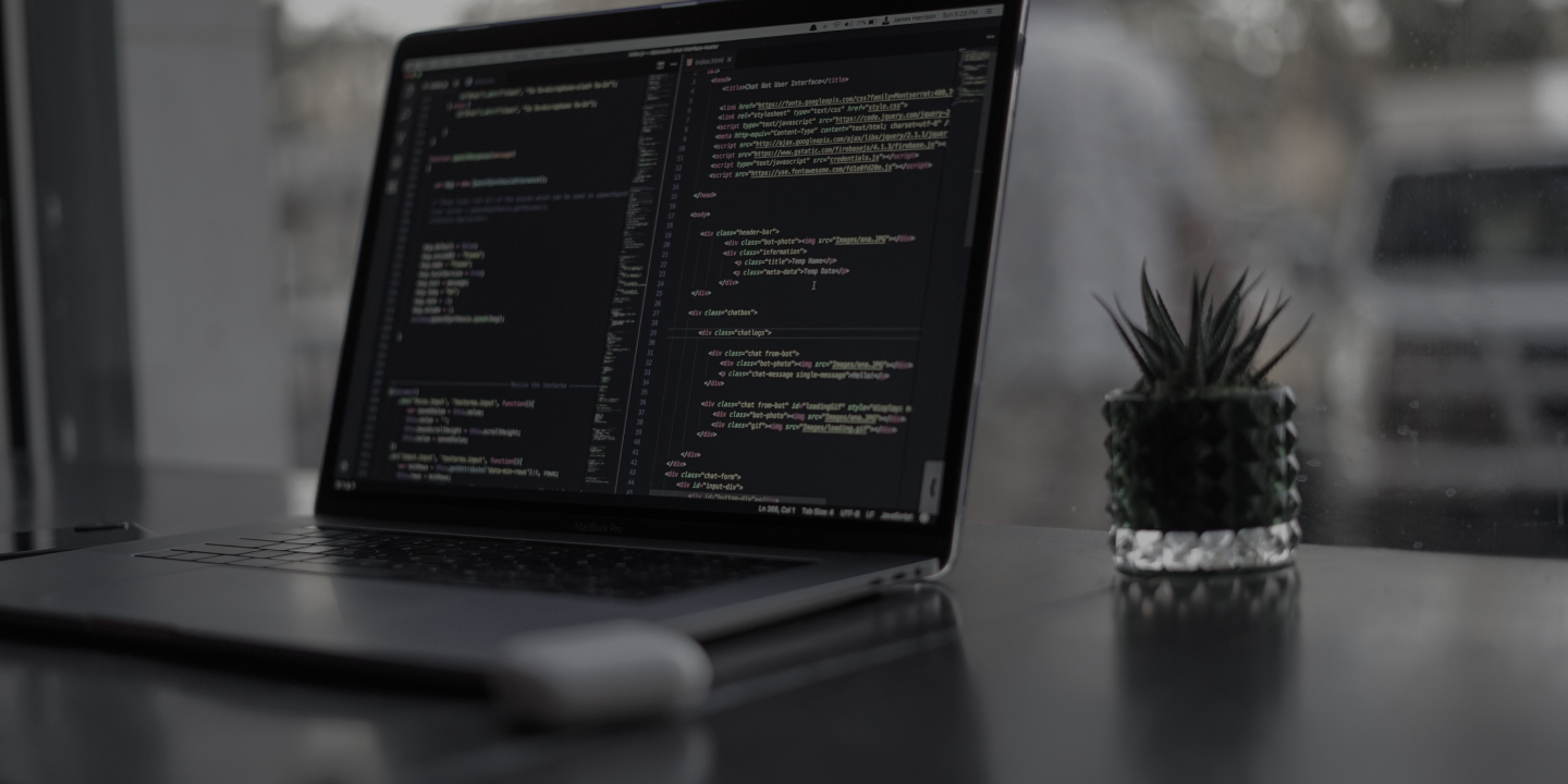 プログラミングコードが入力されたデスク上のノートパソコン