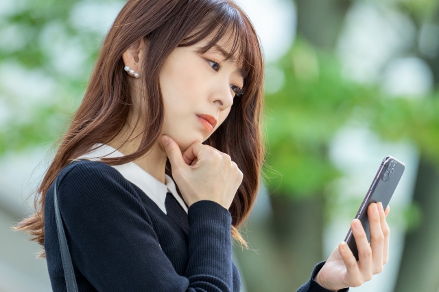 スマホの通知を見て考えるキャリアウーマン