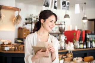 Female café worker holding a tablet for running an online store