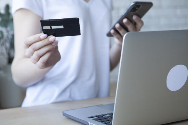 A woman operating a smartphone while holding a credit card